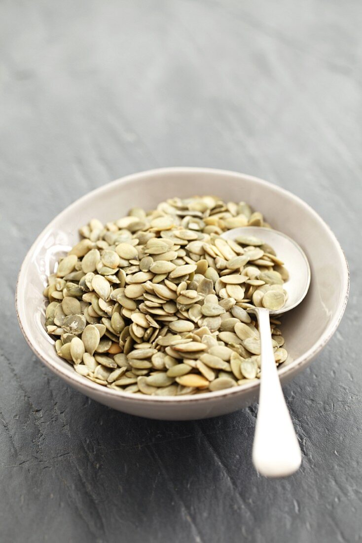 Pumpkin seeds in a bowl with a spoon