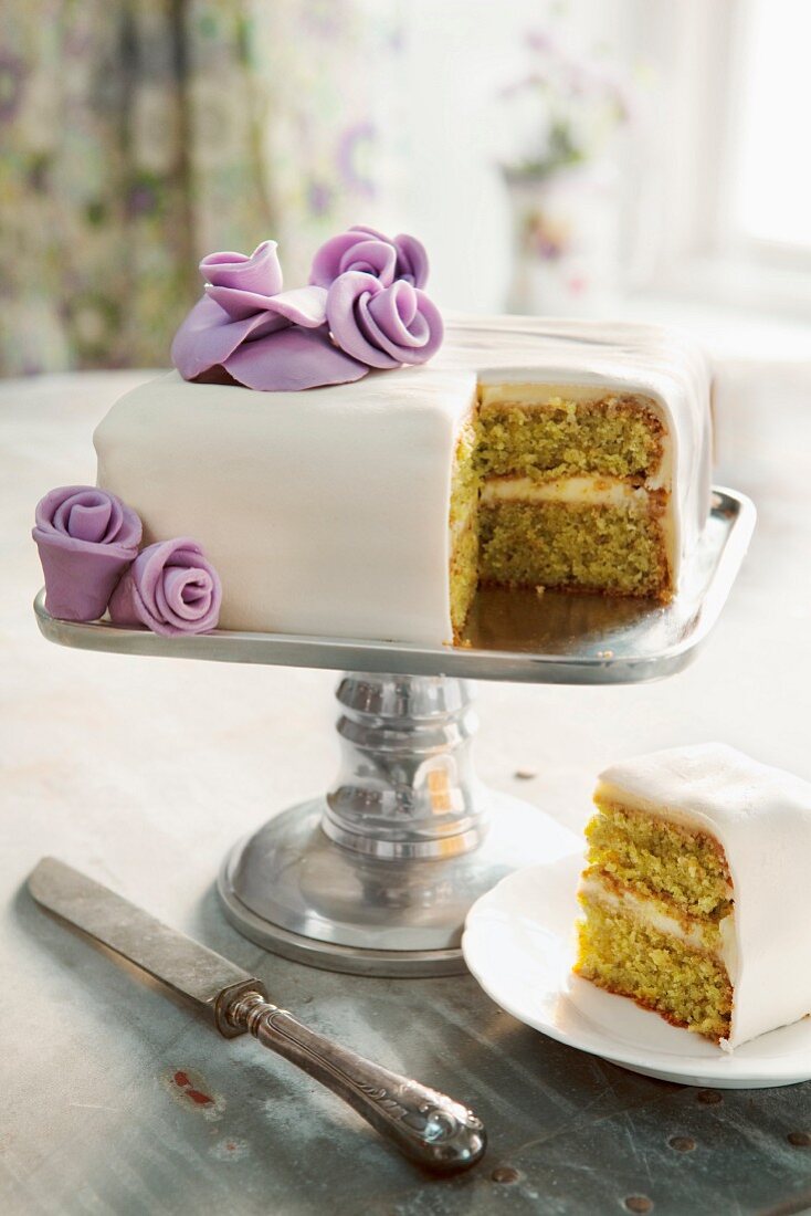 A wedding cake with purple flowers, with one slice cut