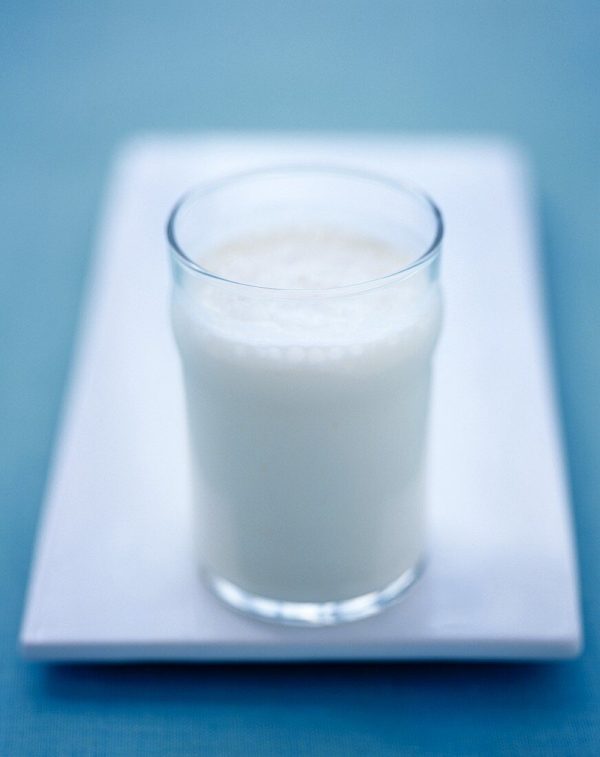 Ein Glas Milch auf weisser Servierplatte