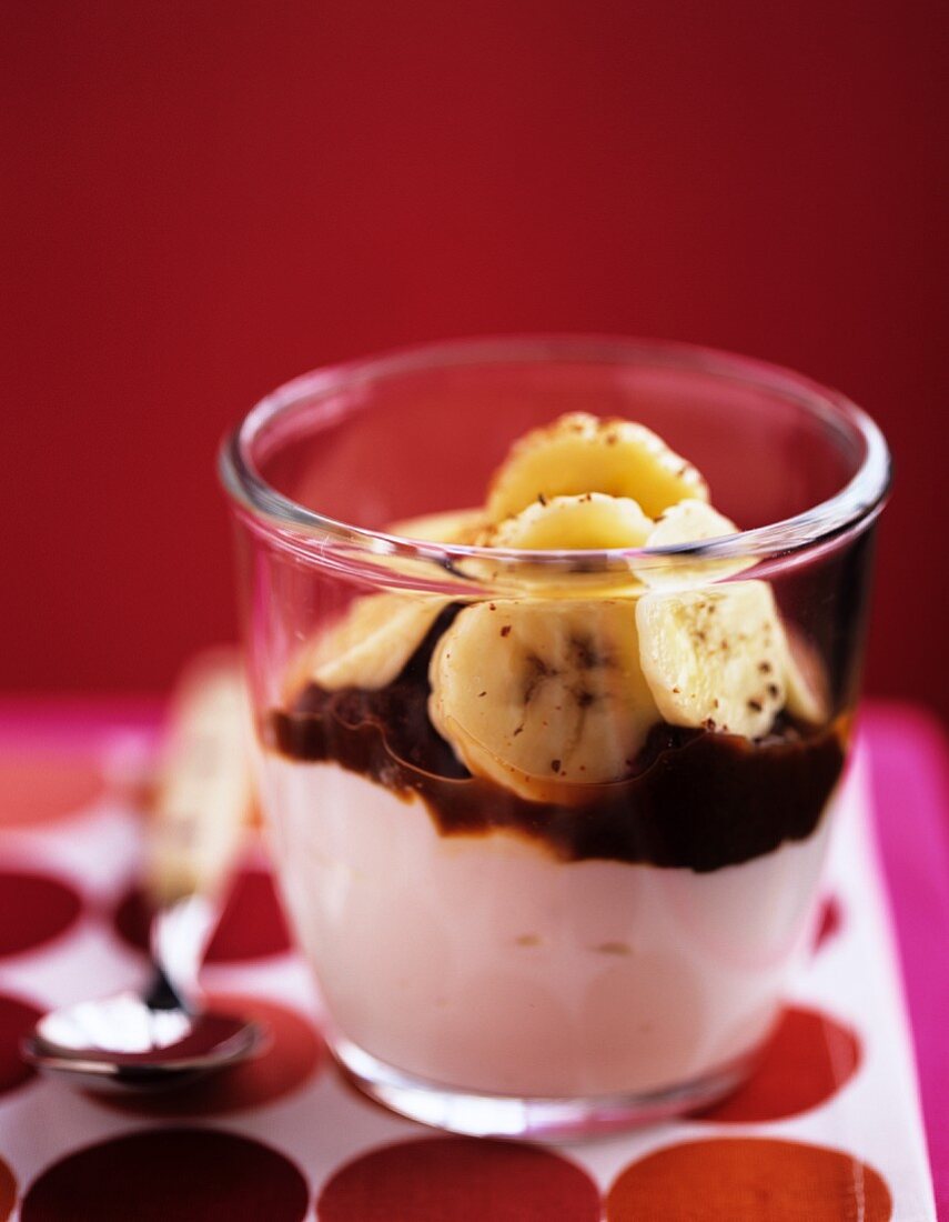 A yoghurt dessert with chocolate sauce and bananas