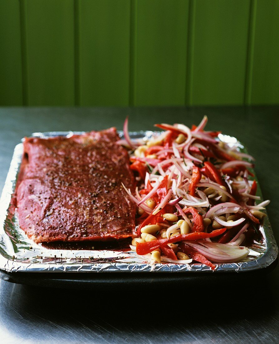 A joint of beef and vegetables in a roasting tin with aluminium foil