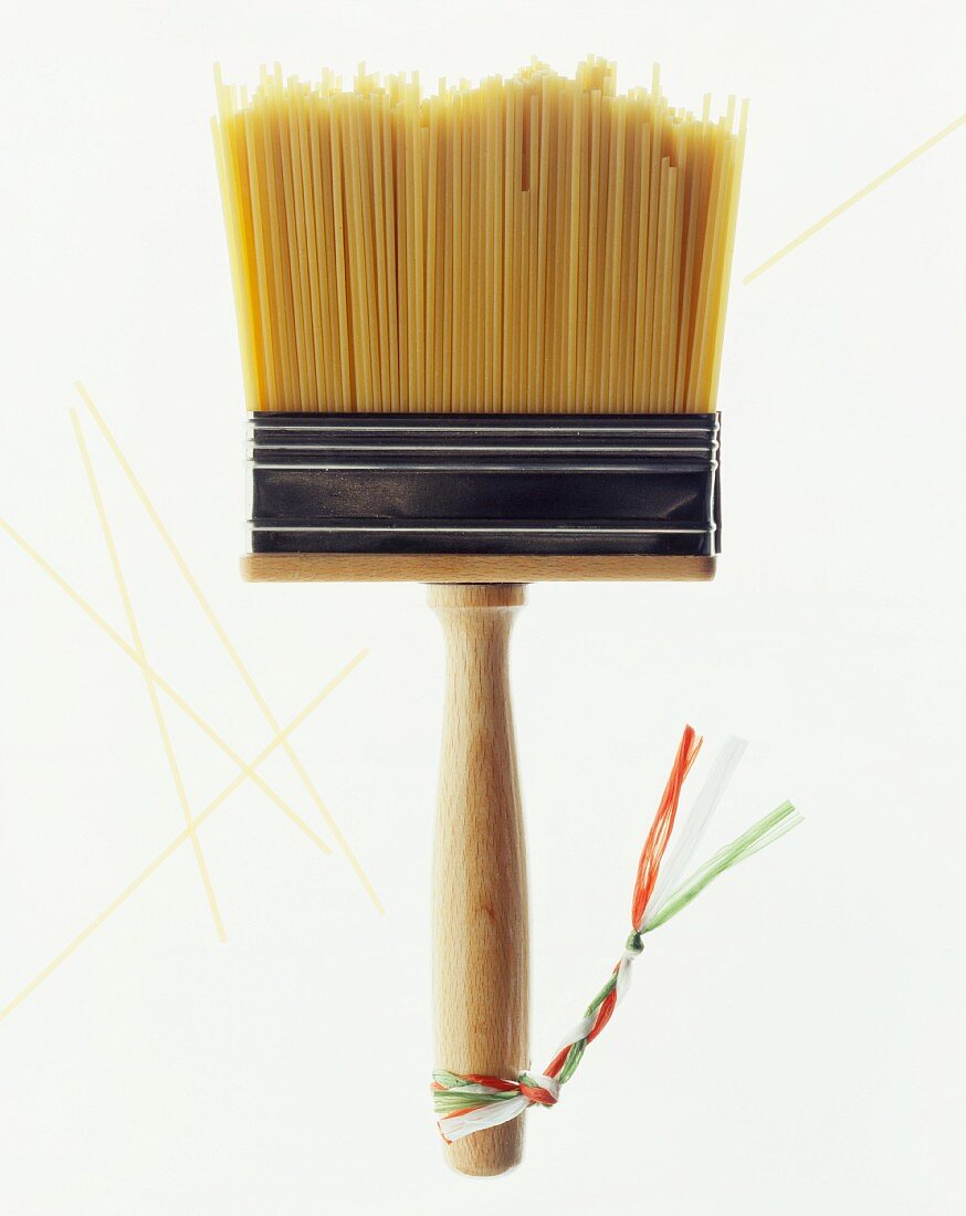 A paintbrush with bristles made of spaghetti and little ribbons in the Italian colours