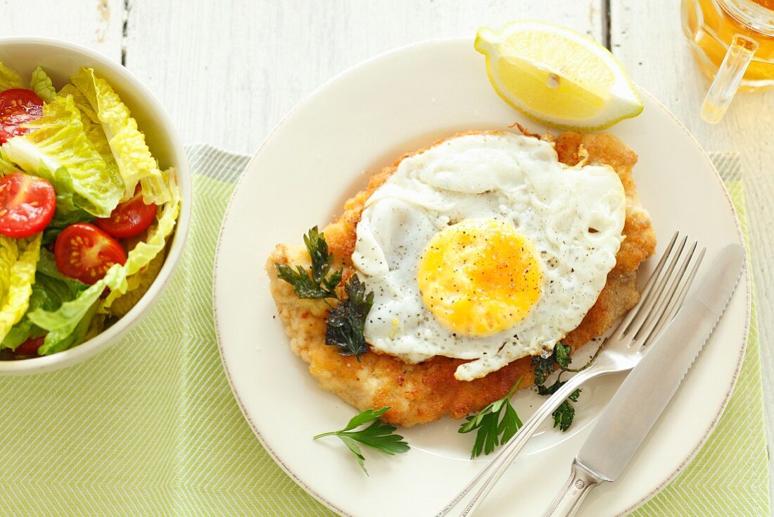 Veal schnitzel with a fried egg, lettuce and beer