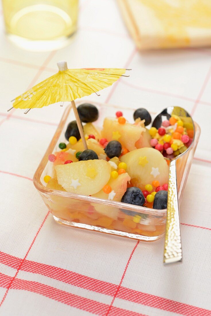 Fruit salad with white peaches, blueberries and a cocktail umbrella