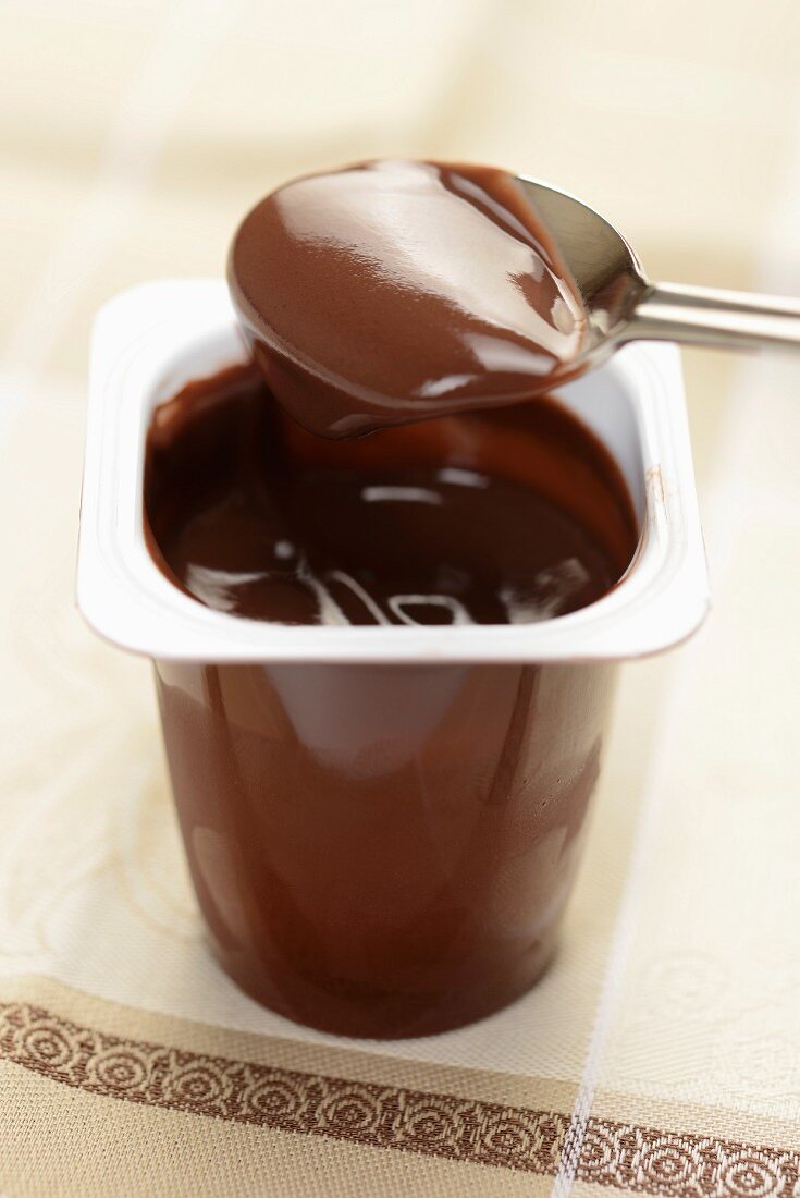 Ein Becher Schokoladenjoghurt mit Löffel