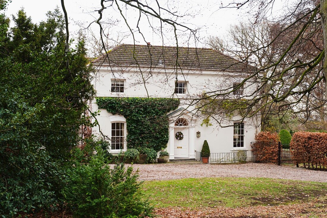 Blick über herbstlichen Garten auf traditionelles englisches Landhaus