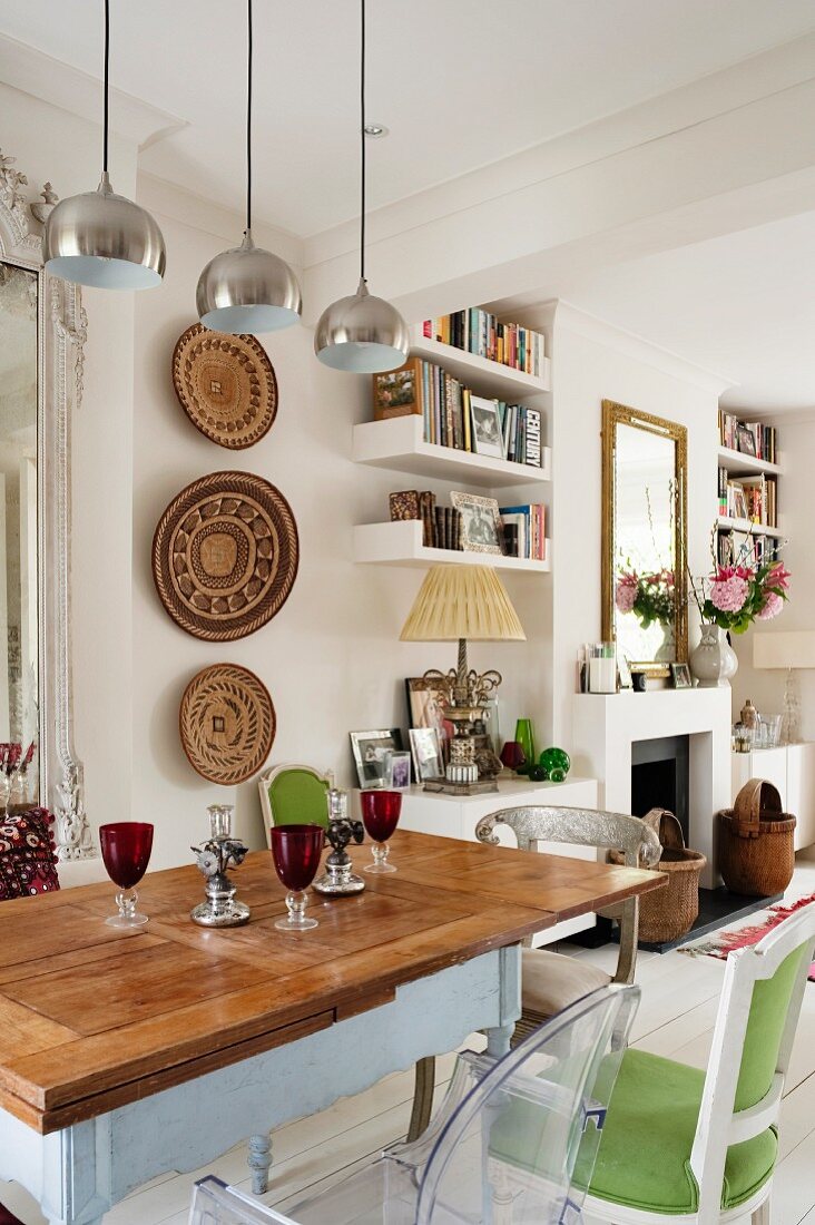 Country-house-style dining table and African wall decorations in open-plan interior