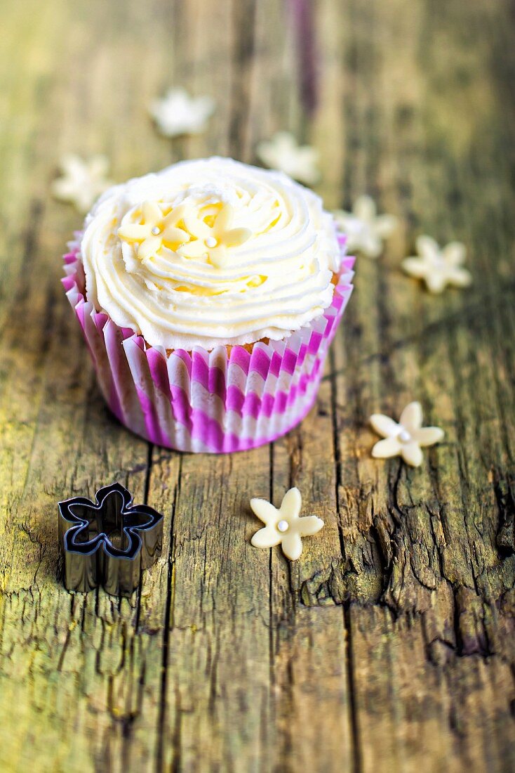 A cupcake with buttercream icing and marzipan flowers