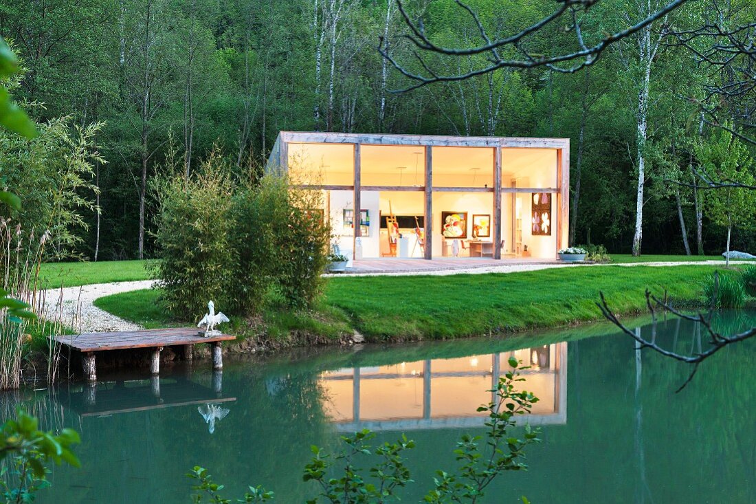Twilight atmosphere; contemporary studio building beside pond in grounds of historical mill in the Dordogne