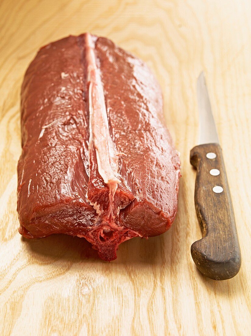 Raw saddle of venison with a sharp knife