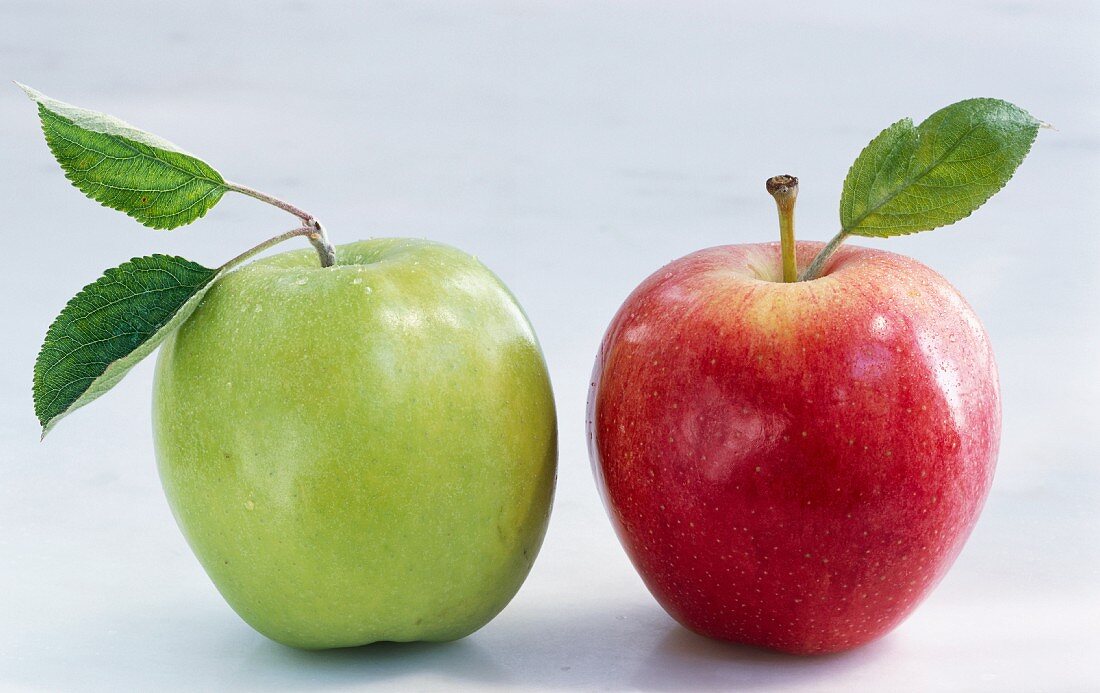 Ein roter und ein grüner Apfel mit Blättern