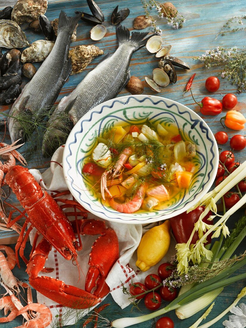 A bowl of fish soup, surrounded by ingredients