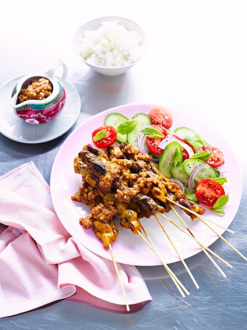 Satay skewers with a cucumber and tomato salad and satay sauce