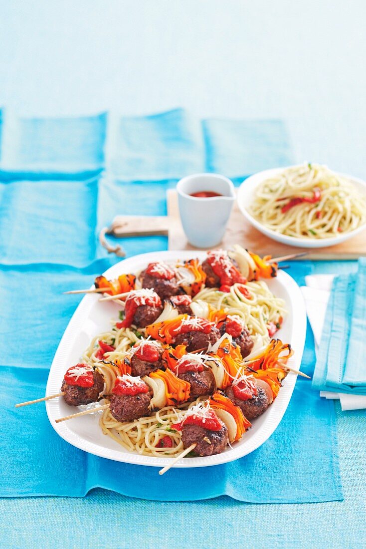 Meatball skewers with vegetables on spaghetti