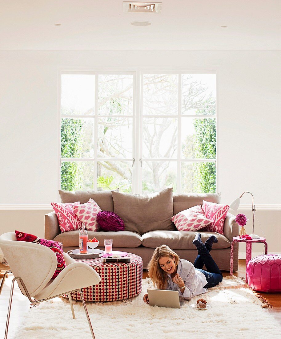 Pinke Farbakzente im Wohnzimmer: Sofakissen, Blume, Sofatisch und Bodenkissen