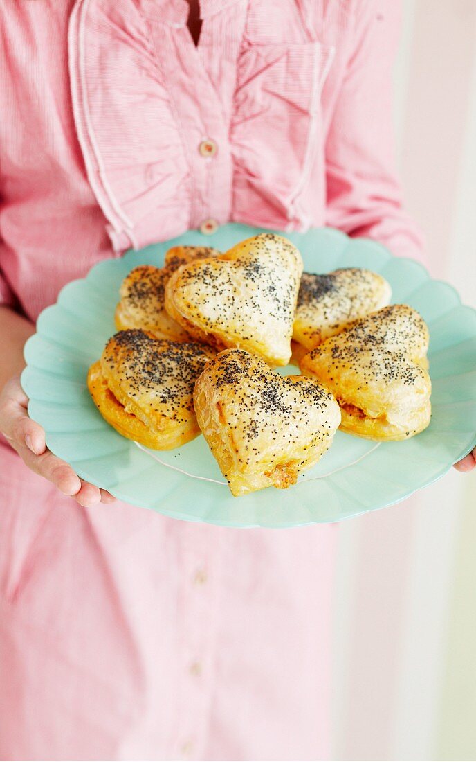 A woman holding a plate of savoury puff pastry hearts
