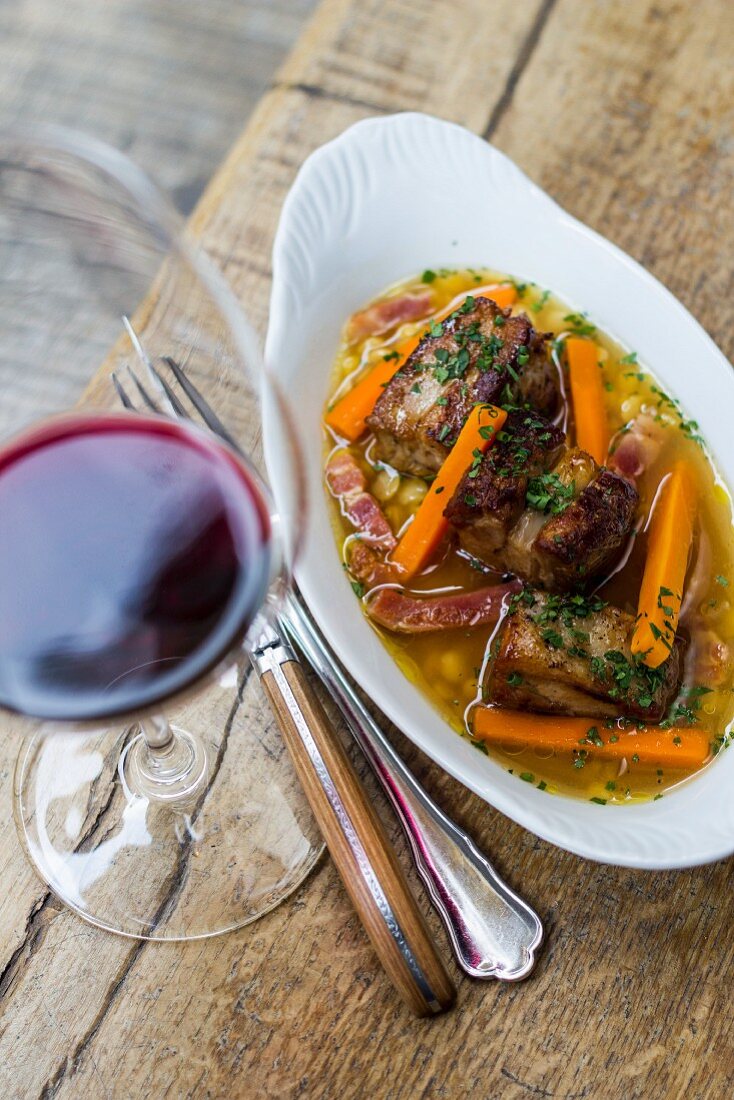Pork short ribs with bacon carrots, and glass of red wine