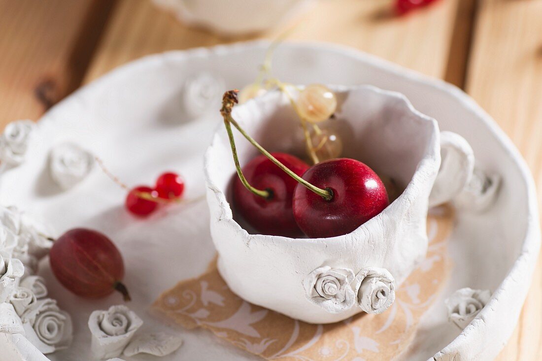 Sweet cherries, redcurrants and red gooseberries in a clay cup