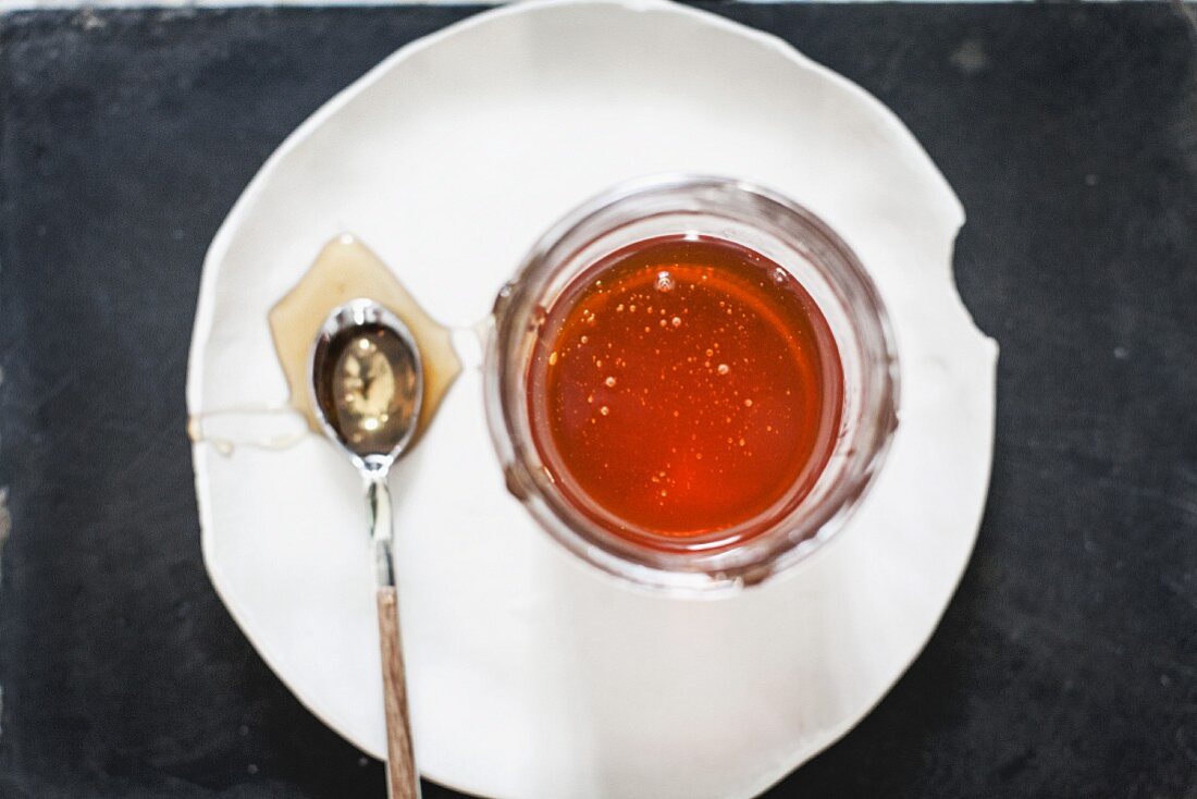 Honigglas und Löffel auf Teller