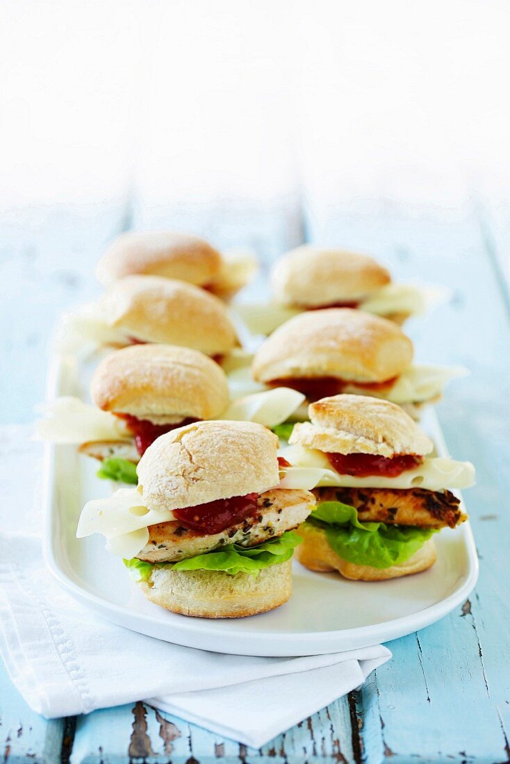 Mini burger buns filled with chicken, lettuce, cheese and tomato sauce