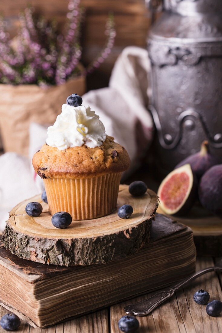 Blueberry cupcake with cream against a rustic background