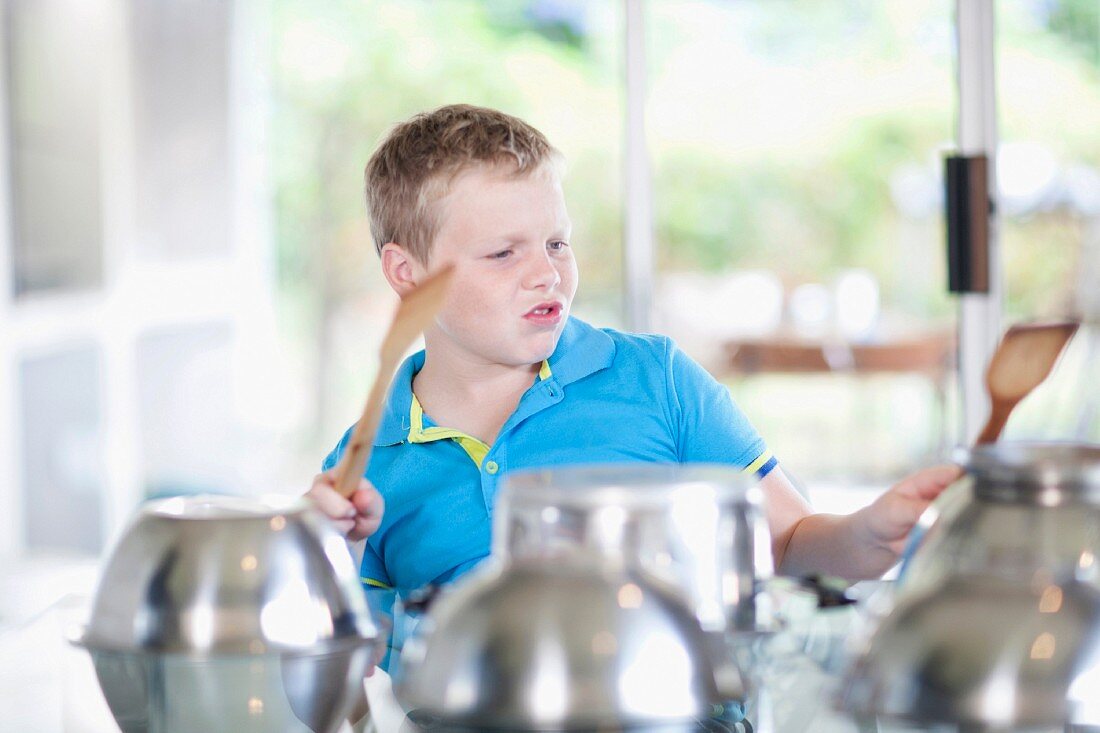 A boy using saucepans as a drum kit