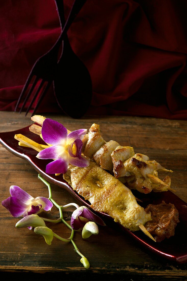 Chicken satay skewers and orchids (Thailand)