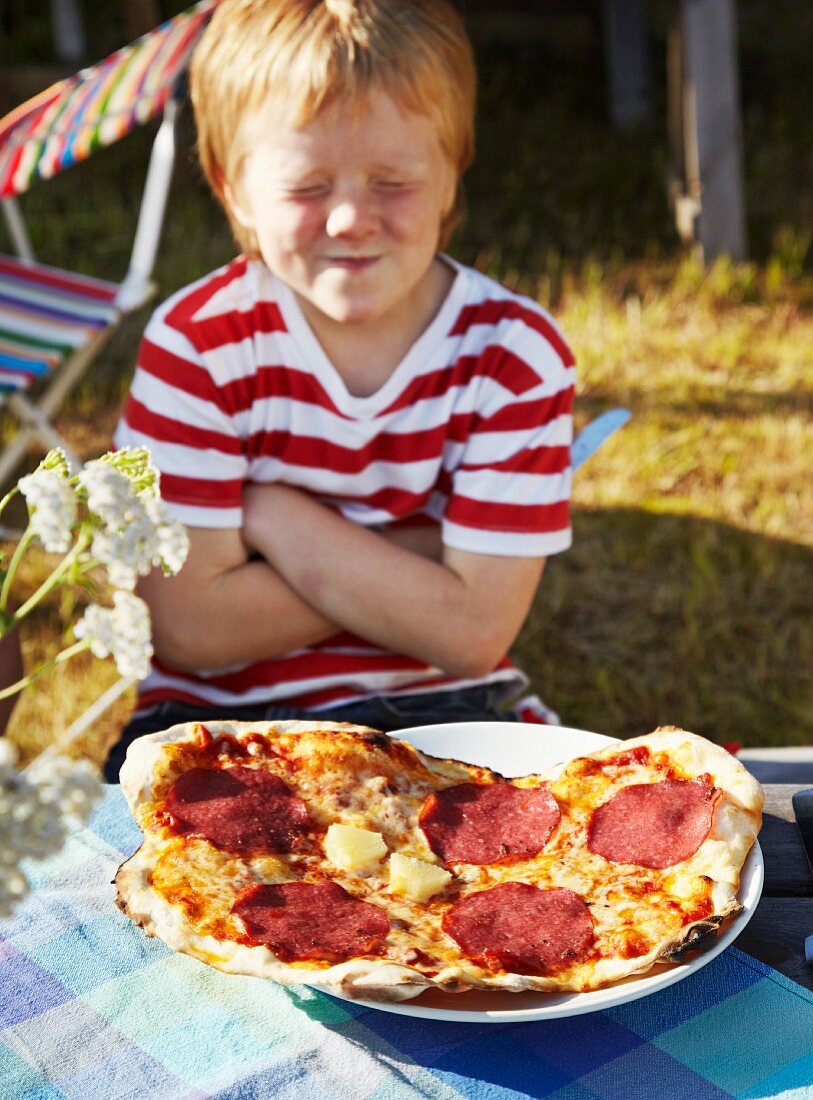 Boy sitting with pizza, eyes closed
