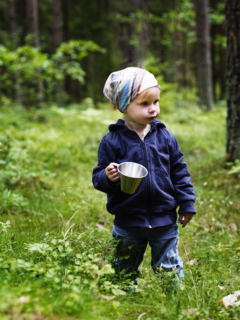 Little girl holding pot in summer forest