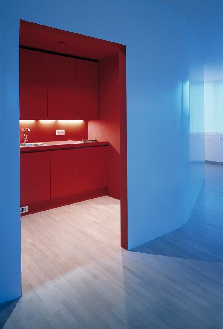 View into red-painted kitchen through open doorway