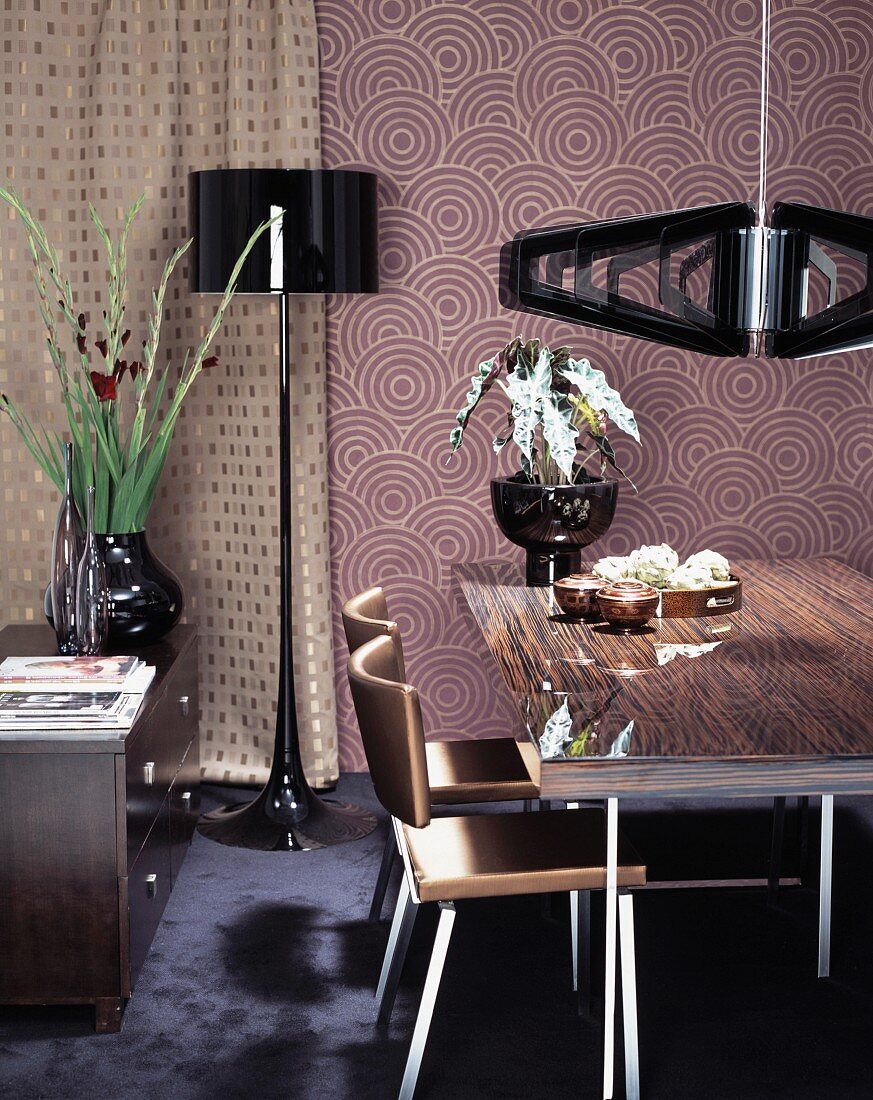 Esstisch und Stühle unter Designer Hängelampe vor Retro Tapete an Wand