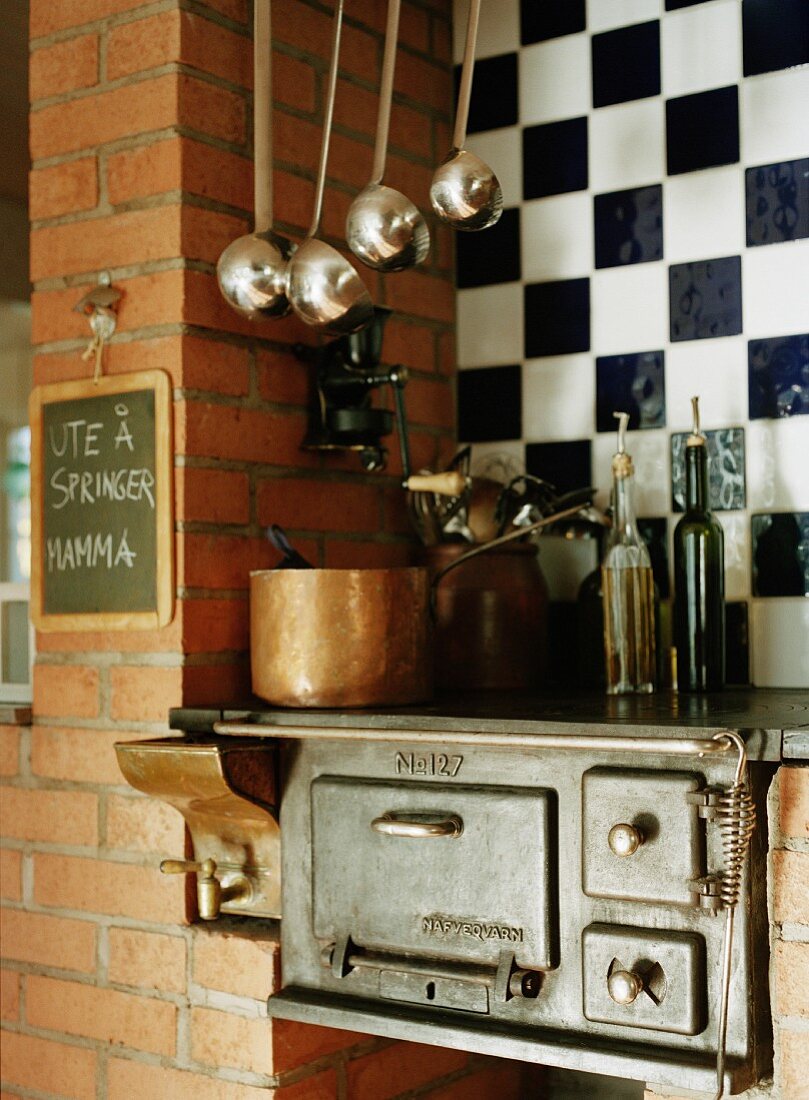 Vintage Küchenherd in Ziegelwand eingesetzt vor Wandfliesen im Schachbrettmuster