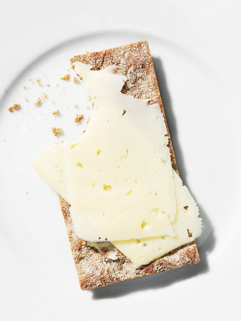 Close up of crispy bread with butter and cheese on plate