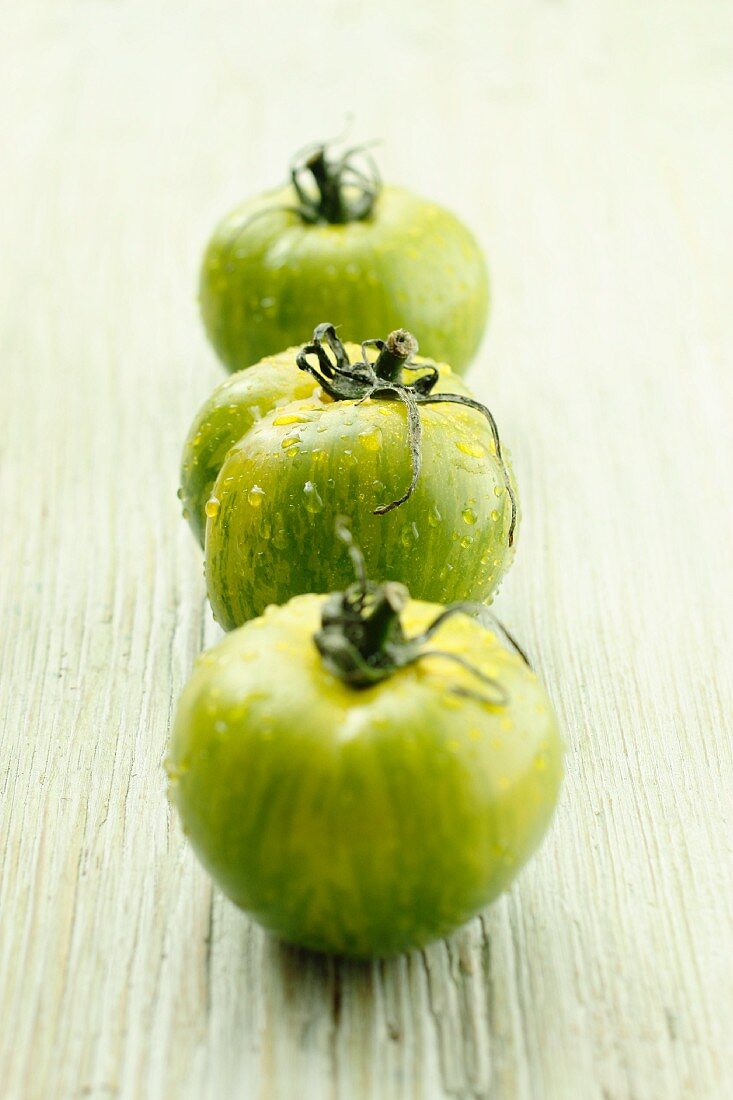 Three green tomatoes with water droplets