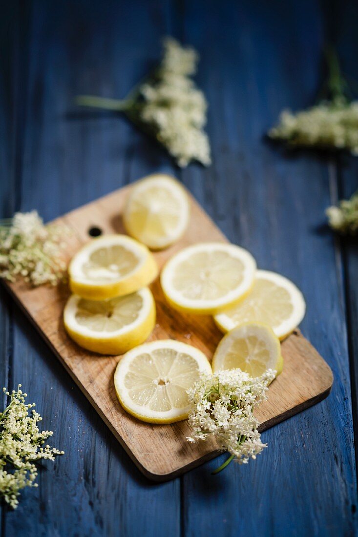 Lemon slices and elderflowers on a small wooden board