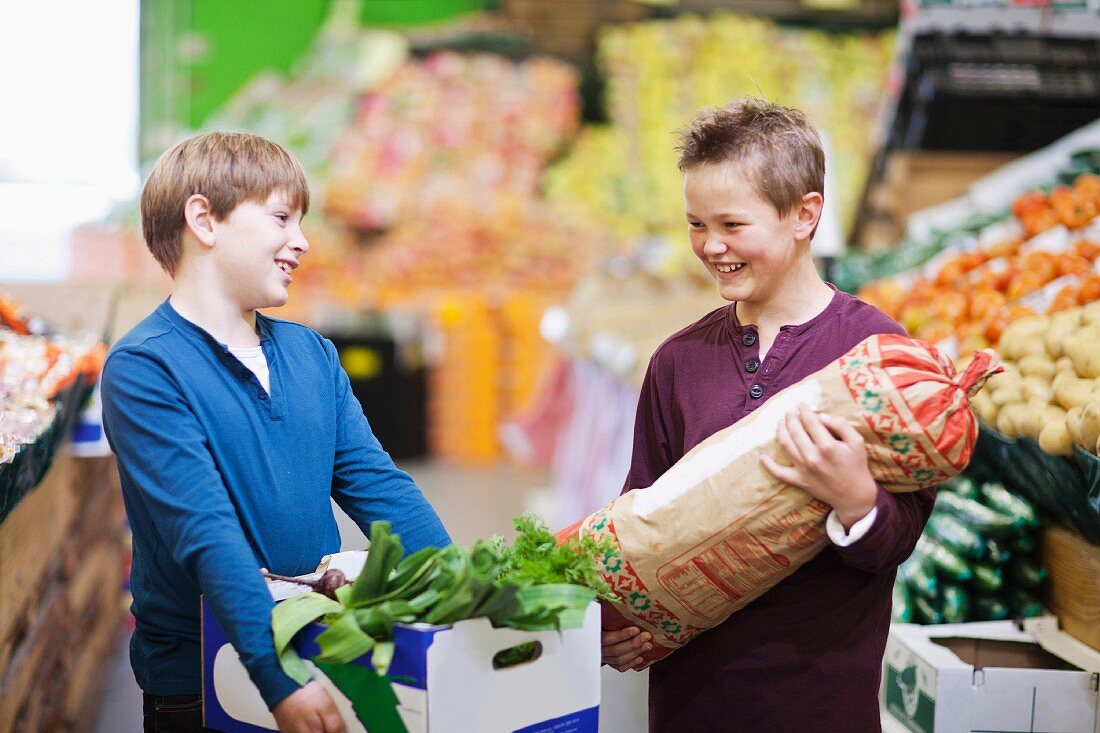 Zwei Jungen mit Kartoffelsack und Gemüsekiste in einem Supermarkt