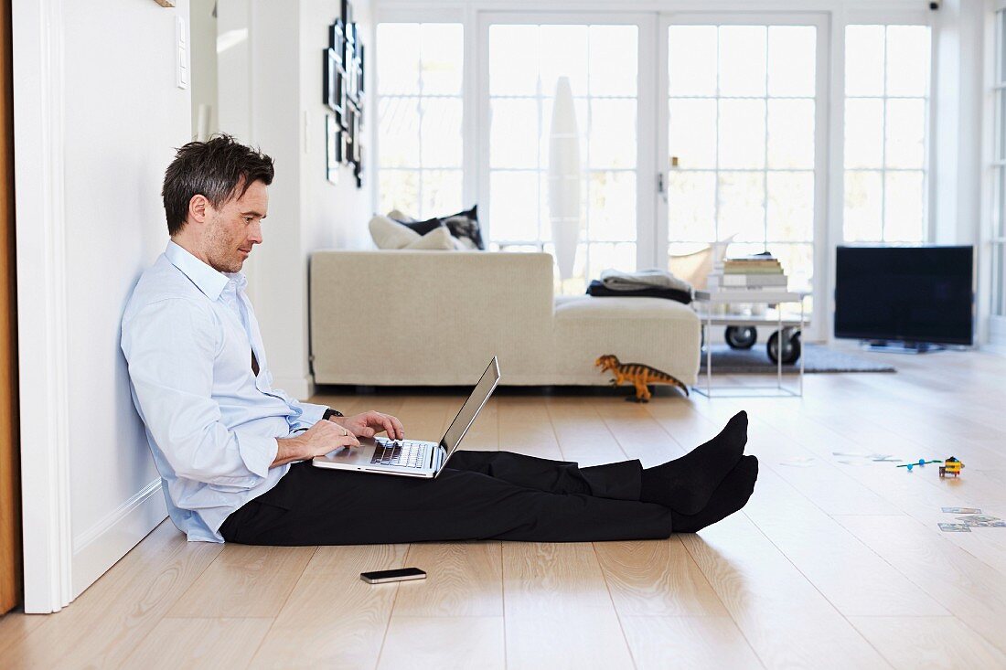 Man sitting on floor using laptop