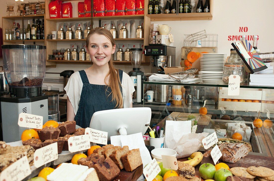 Junge Frau hinter der Kuchentheke in einem Café