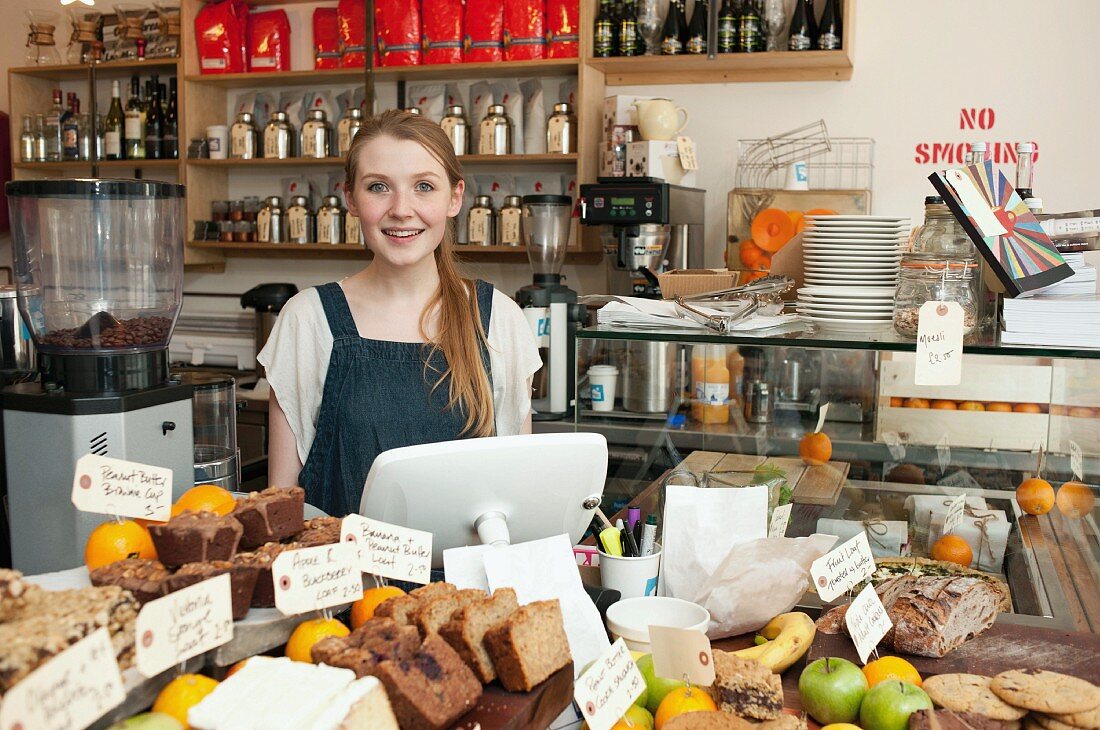 Young woman behind kitchen counter in cafe