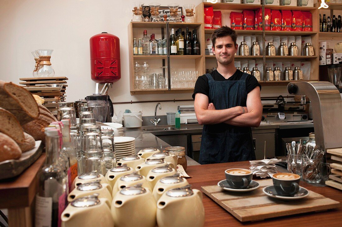 Portrait of young man behind kitchen counter in cafe