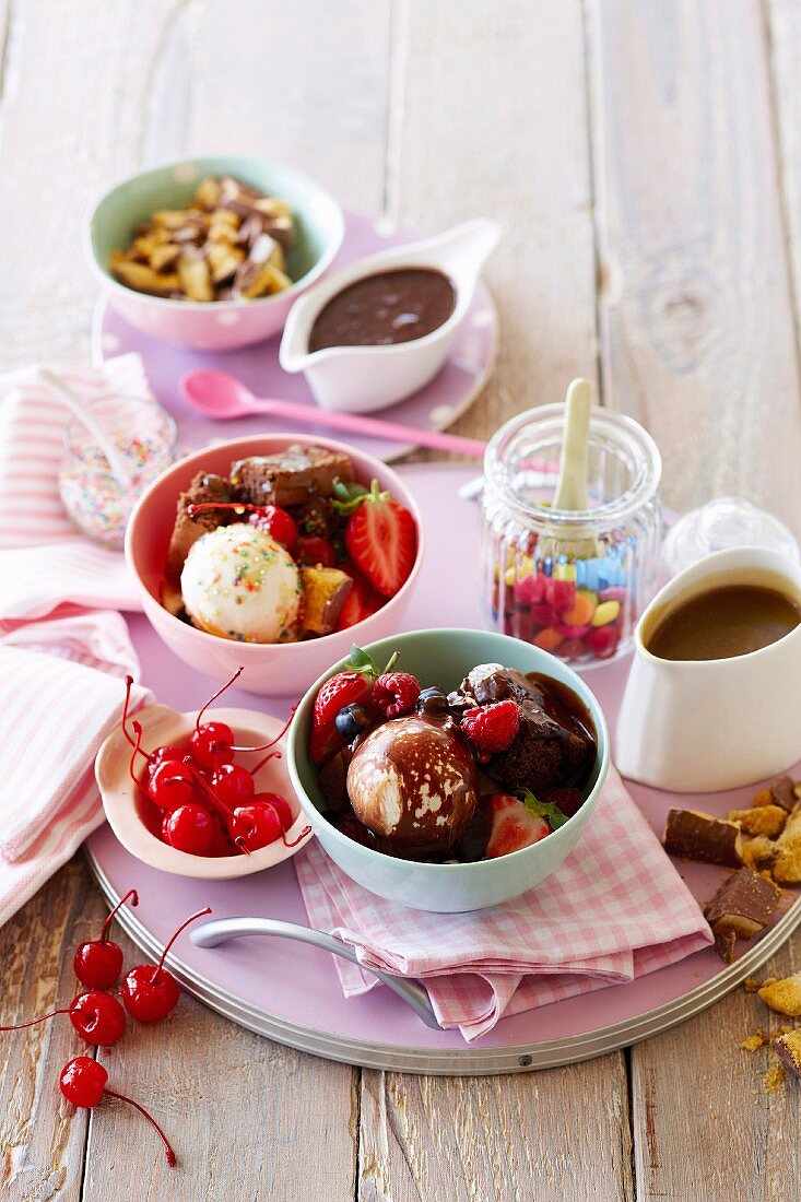 Bunte Eisbecher mit Früchten und verschiedenen Saucen