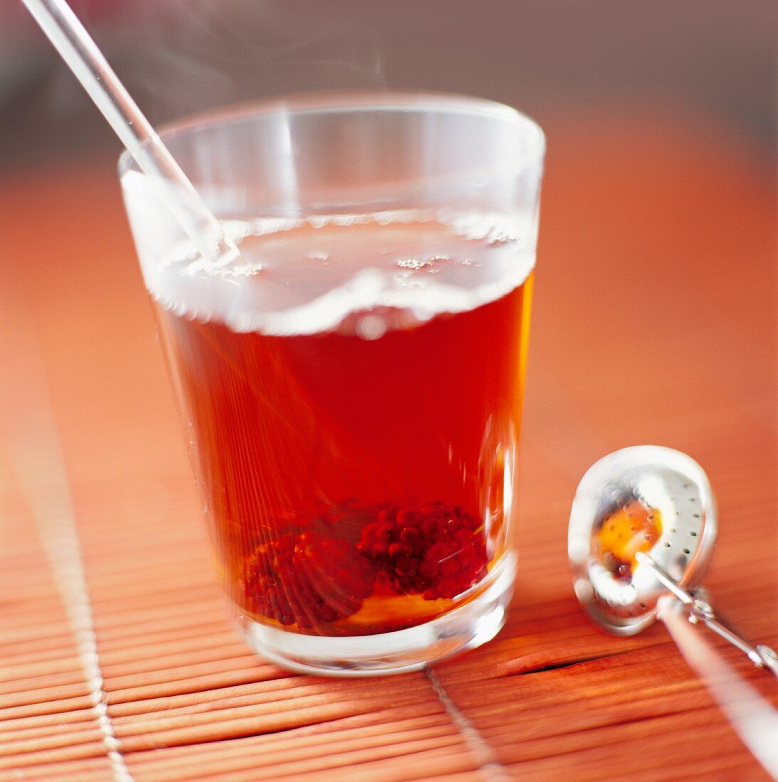 Früchtetee im Glas neben Teeei