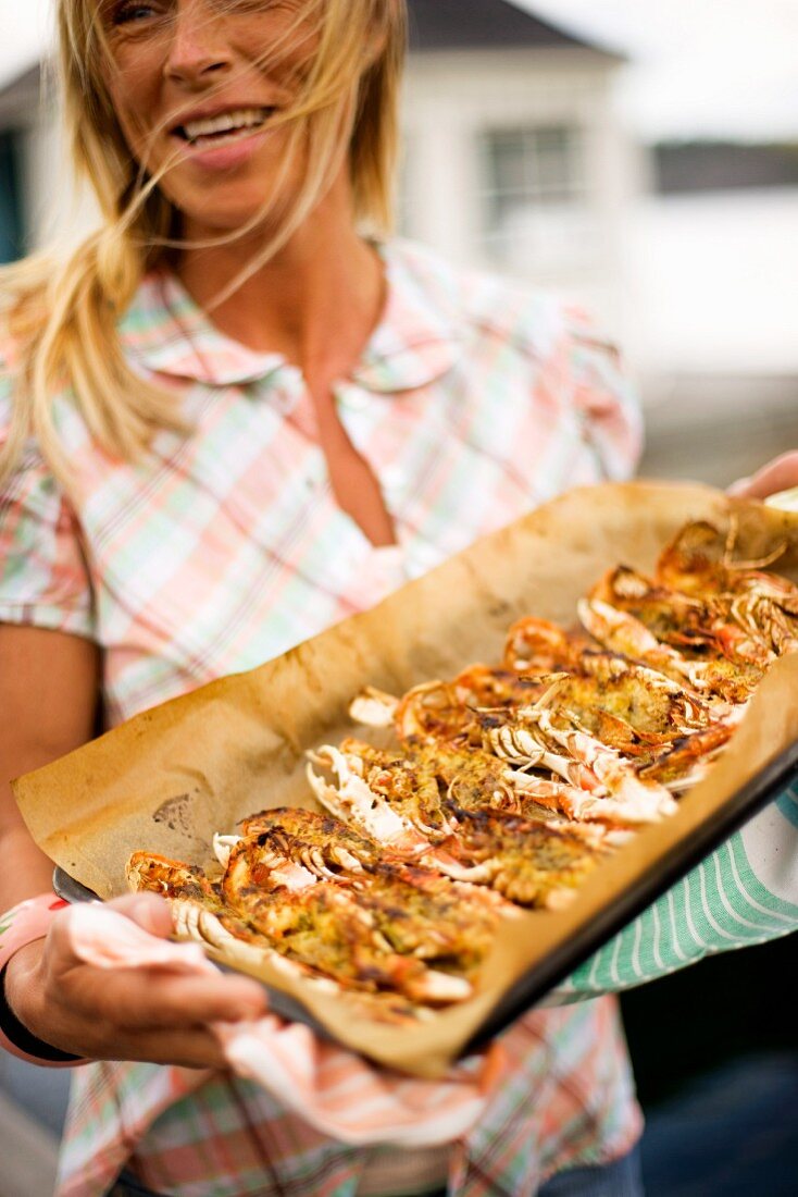 Blonde Frau serviert Backblech mit Meeresfrüchten