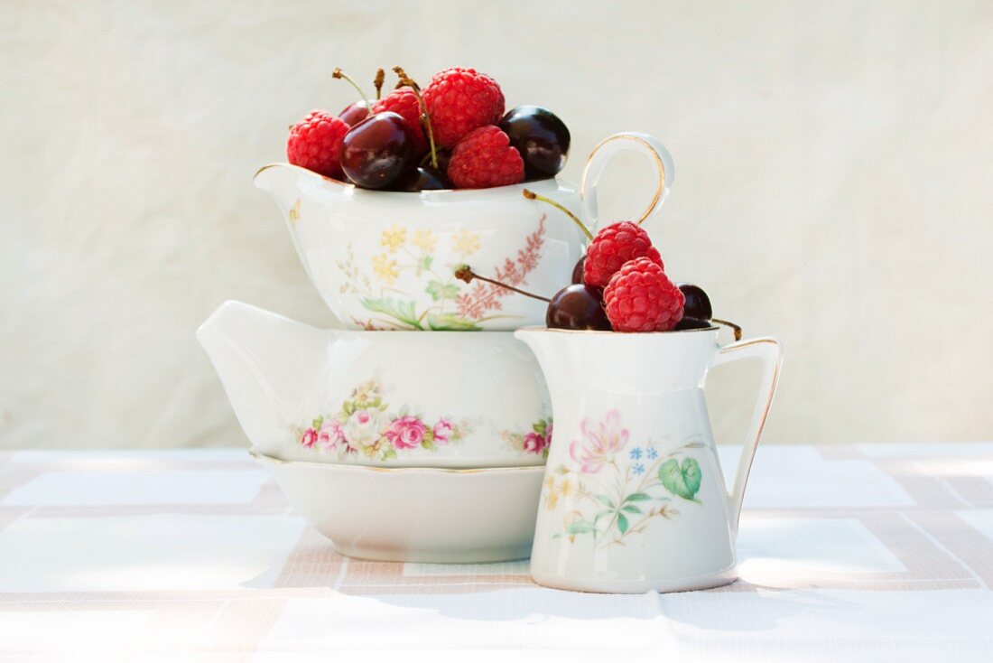 Raspberries and cherries in old milk jugs