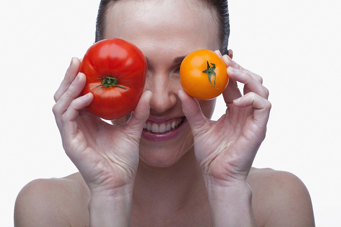 Lachende Frau mit roter und gelber Tomate