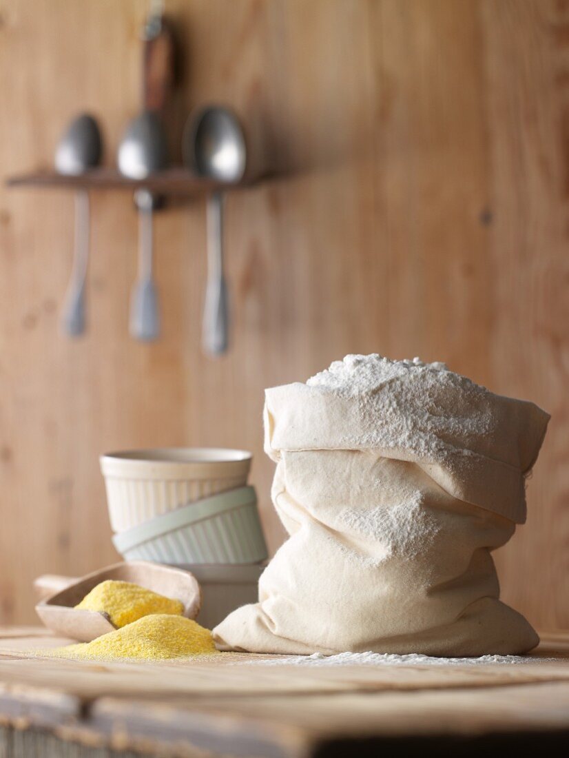 A bag of flour, polenta and baking moulds on a wooden table