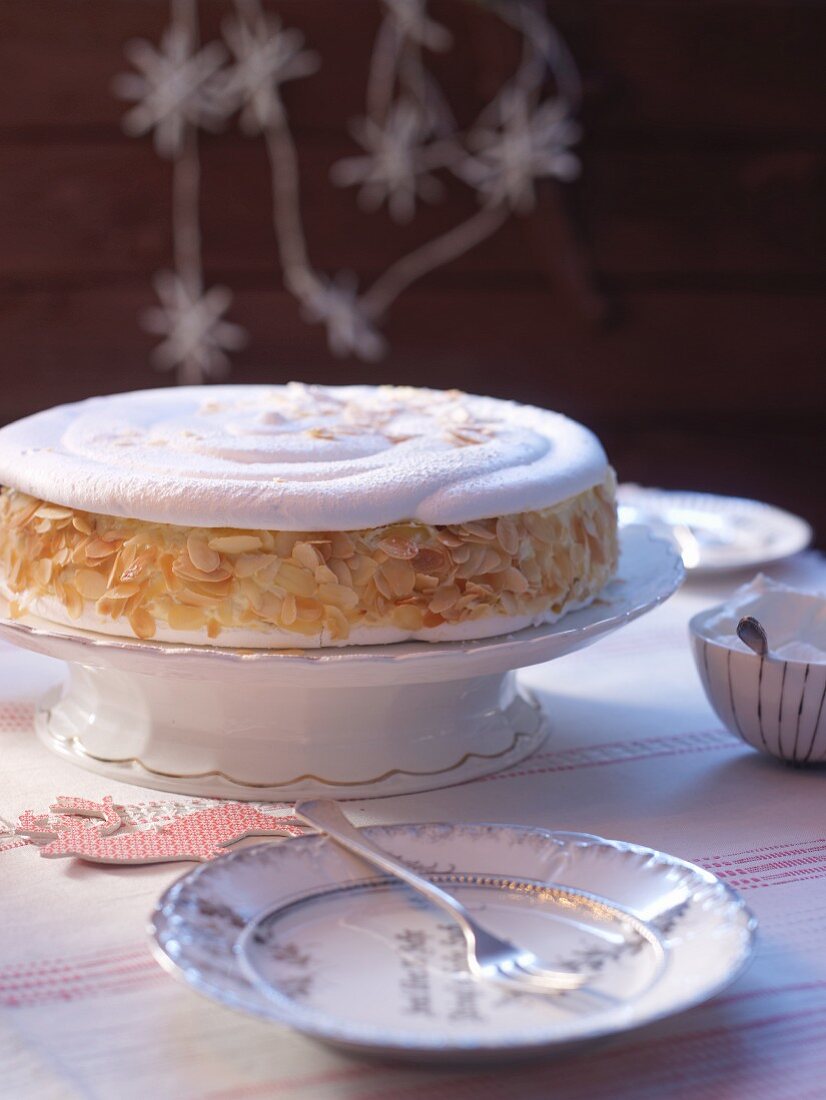 Baisertorte mit Mandelblättchen auf Tortenständer (weihnachtlich)