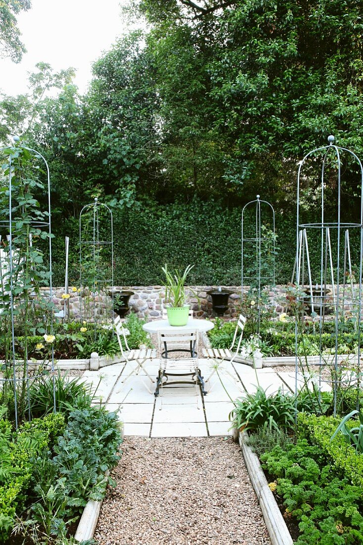 Symmetrisch angelegte Gemüsebeete; im Hintergrund kleine Springbrunnen in Pokalform