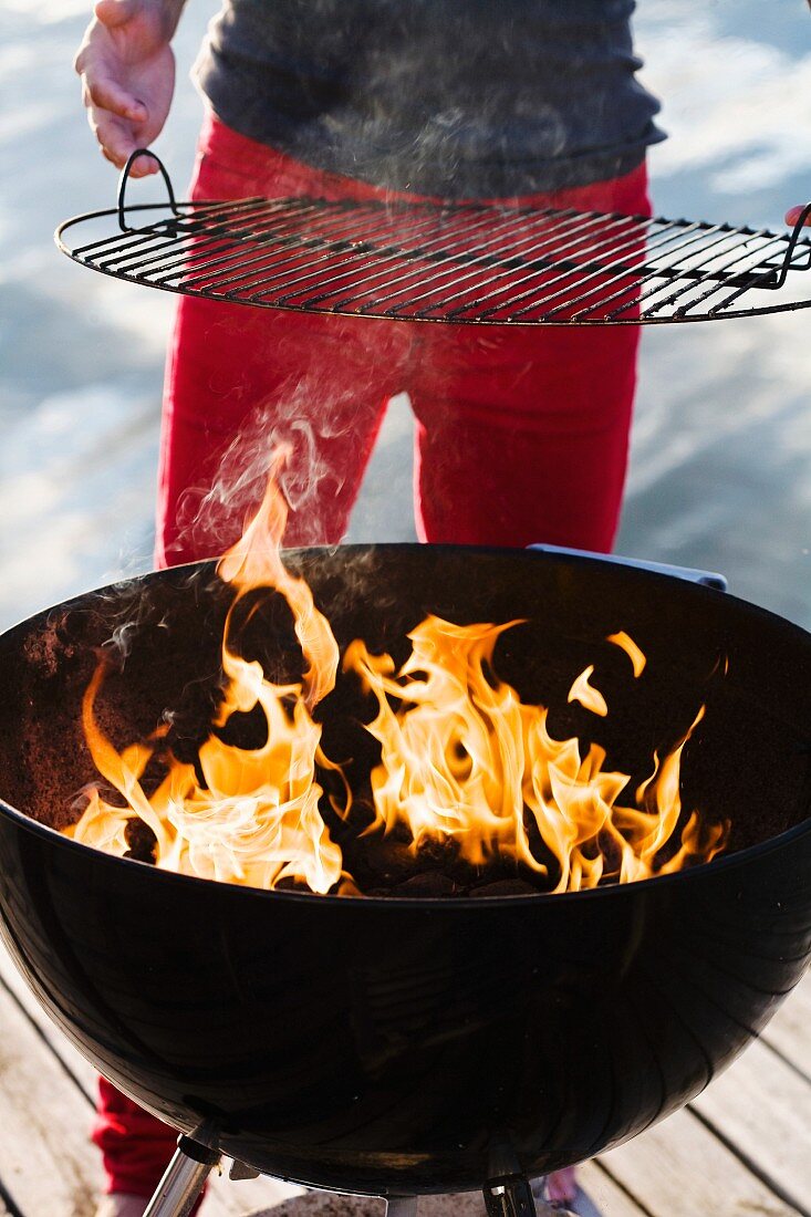 Man standing on jetty holding barbecue grill