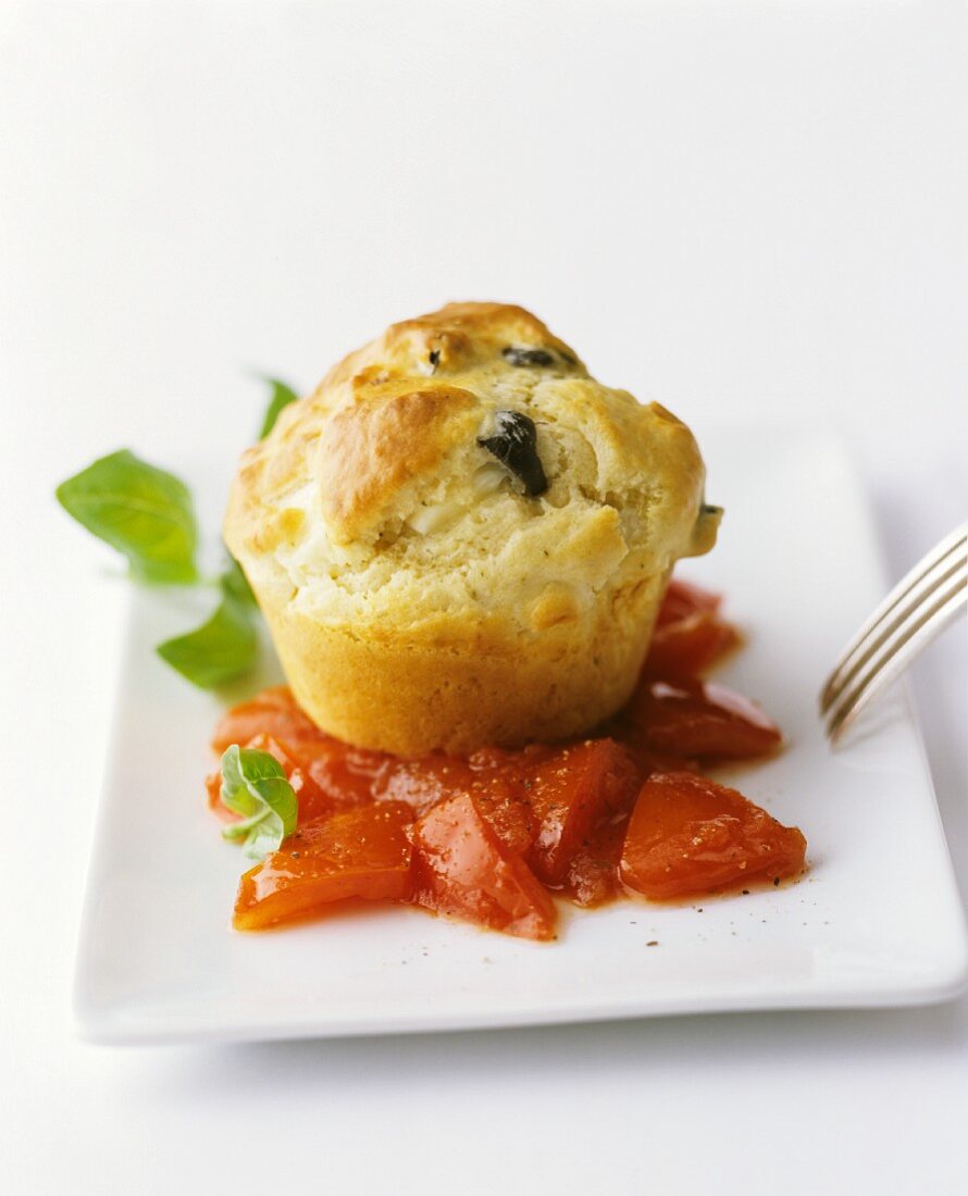 An olive muffin on tomatoes with basil